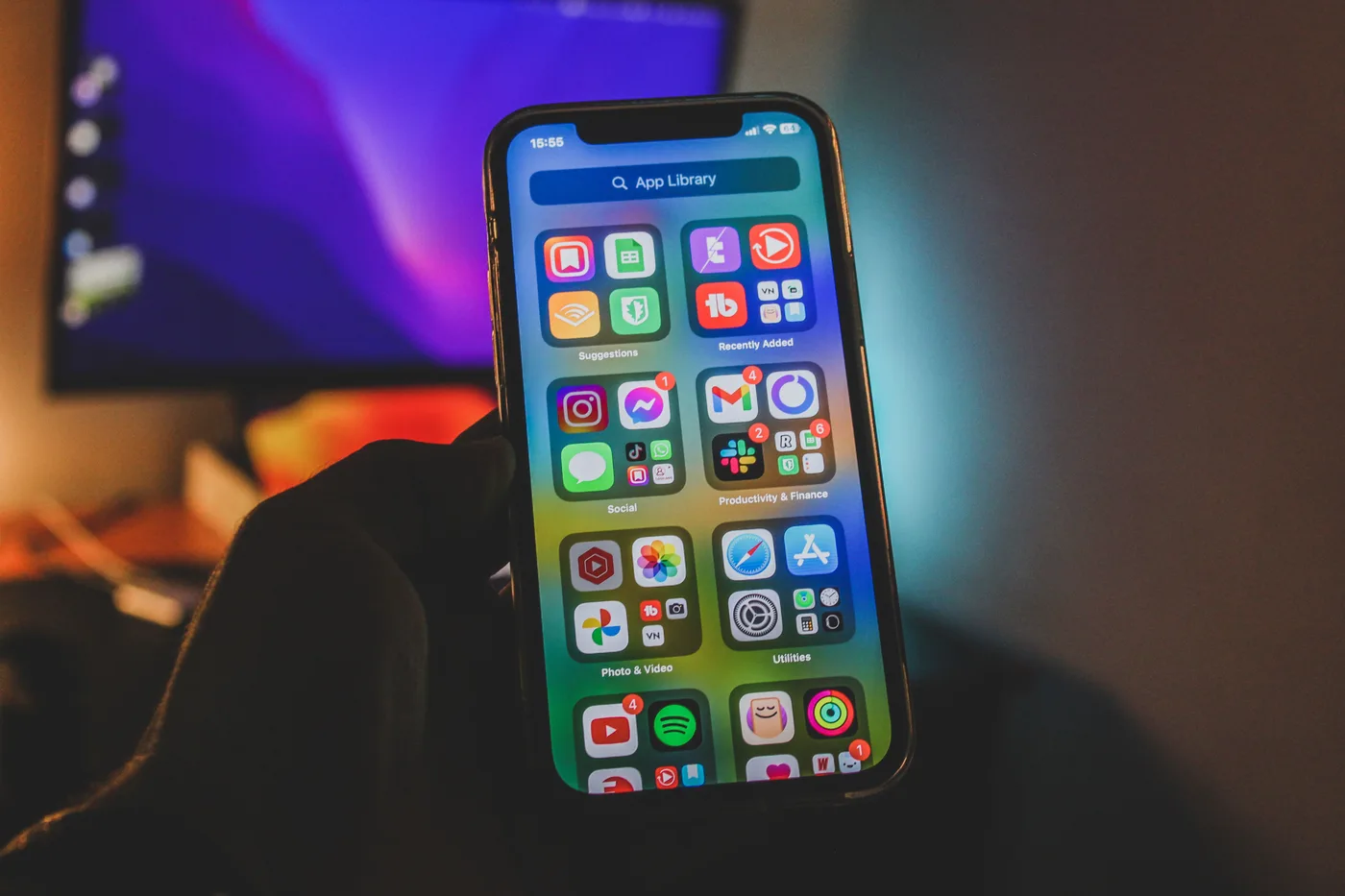 Rankoje laikomas telefonas su ekrane matoma programėlių biblioteka