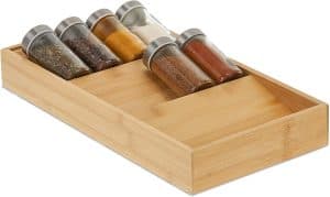 Prieskoniai stikliniuose indeliuose su etiketėmis, sudėti stalčiuje su nuolydžiu