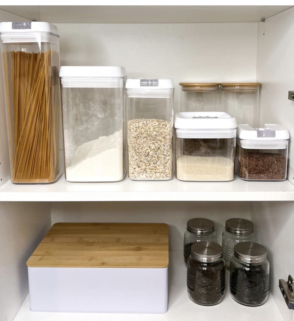 Šviesi virtuvė su tvarkingais stalčiais ir šviesos žaismu ant stalviršio